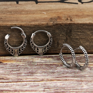 Vintage silver titanium steel hoop earrings with ethnic patterns on a wooden background