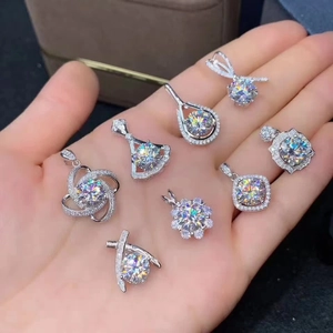 Macro shot of assorted round cut moissanite pendants in silver finish held in hand