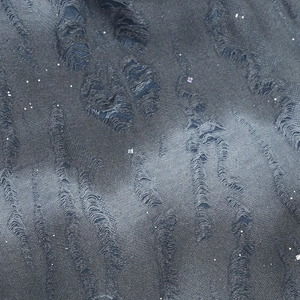 Macro shot of dark denim fabric with distressed brushed texture and silver glitter sequins