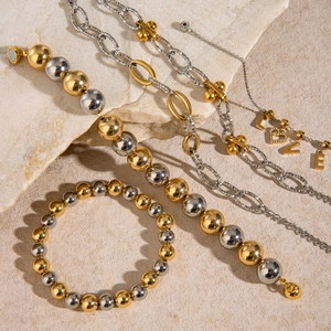 Dettaglio dei bracciali a sfere bicolore e collana con ciondolo LOVE su pietra