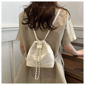 Detailed back view of a white pleated drawstring bucket backpack with chain strap