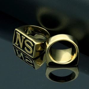 Close-up of men's gold punk signet ring featuring black NS letter engraving details