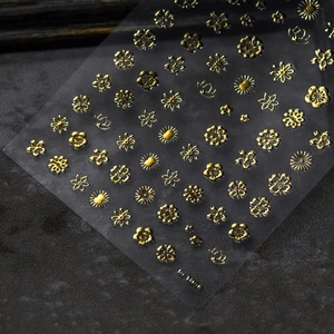 Vista macro di adesivi per unghie 3D dorati con motivi floreali a rilievo e dettagli