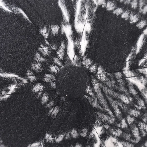 Close-up of black and white plaid thick baseball cap top button and textured fabric detail
