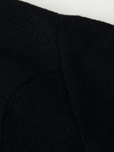 Close-up detail of high-quality black wool blend fabric with professional stitching texture