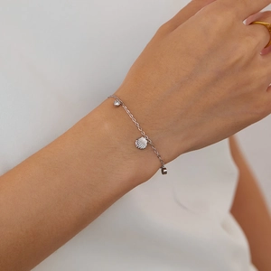Makro-Detail des Silberarmbands mit Muschelanhänger und funkelndem Zirkon-Stein