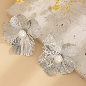 Macro detail of silver ginkgo leaf flower earrings with white pearl centers on stone