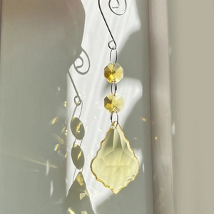 Close-up of yellow teardrop suncatcher casting vibrant rainbow reflections on the wall