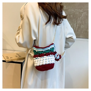 Detailed close-up of handmade crochet cherry bucket bag with pearl chain and knit texture