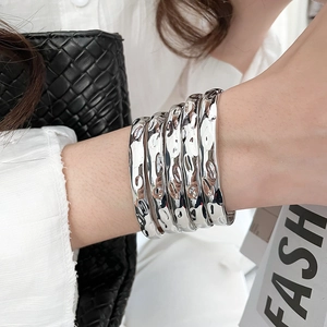 Close-up of stacked silver liquid metal style textured bangles with hammered finish
