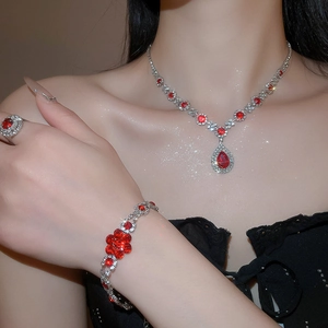 Close-up of luxury jewelry set with red gemstones and silver diamonds on model
