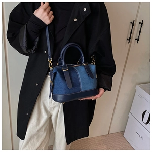 Dettaglio di una borsa Boston in denim color-block con manici in pelle sul modello