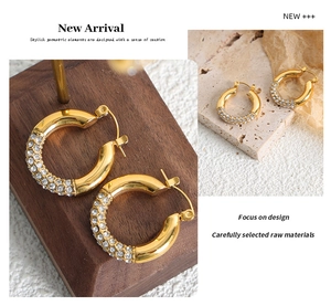 Macro shot of gold-plated hoop earrings with pave-set rhinestones on a wooden display stand