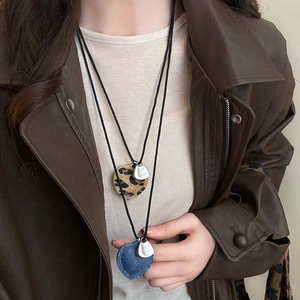 Detail of woven rope necklace with leopard print and denim blue heart pendants
