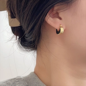 Close-up of minimalist gold U-shaped hoop earrings worn on ear for style demonstration