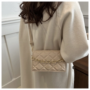 Close-up of beige quilted crossbody bag with gold chain detail and textured finish