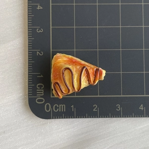 Macro top view of miniature resin slice cake showing glossy glaze and brown sauce details