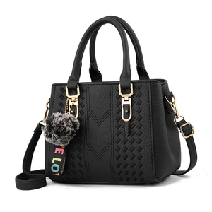 Minimalist black faux leather handbag with pompom charm and adjustable crossbody strap