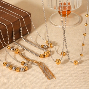 Detail of 18K gold and silver beaded Y-necklace with elegant long tassels on wood