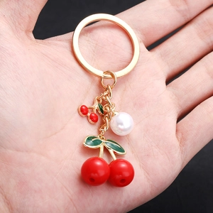 Red cherry keychain with green enamel leaves and white pearl on gold metal ring