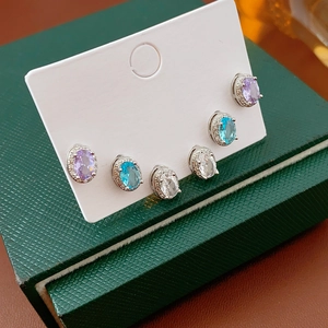 Detail of three pairs of silver earrings with purple, blue, and white oval zircon stones