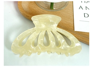 Close-up of cream acetate hair claw clip showing elegant marble texture on wooden tray