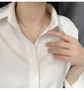 Dettaglio catena argento con pendente quadrato giallo trasparente su camicia bianca