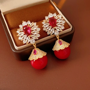 Détails de boucles d'oreilles vintage en or avec gemmes rouges dans un coffret en velours