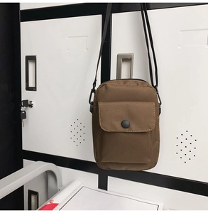 Close-up of brown nylon messenger bag showing adjustable strap and snap-button pocket