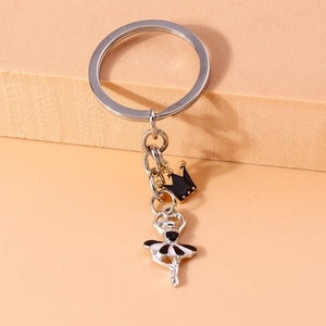 Detail shot of silver ballet dancer and gold crown pendants on a metal keychain