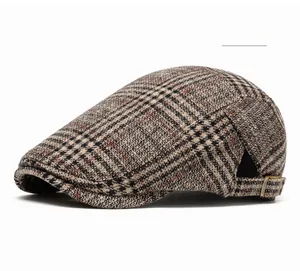 Detail of wine red plaid beret hat with metallic side buckle on white background