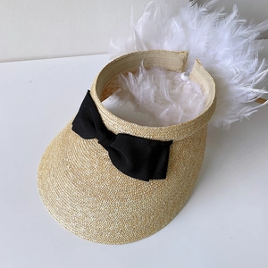 Detail of straw sun visor with black satin bow and elegant white feather decoration