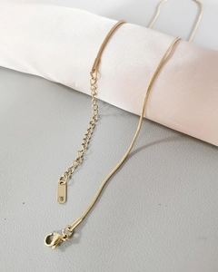 Close-up of gold snake chain necklace with lobster clasp and adjustable extender chain
