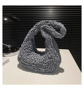 Detail of grey pleated cloud bag showing unique bubble popcorn texture on white surface