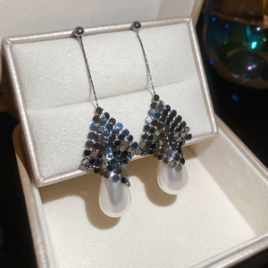 Macro detail of silver sequin mesh earrings with large teardrop pearl drop pendants