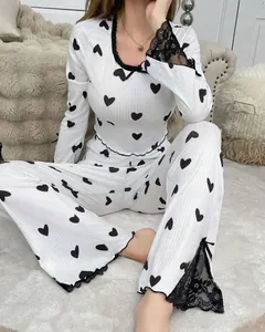 Detail of white ribbed knit pajamas featuring black heart prints and lace trim accents