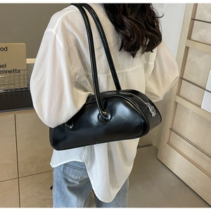 Detailed view of a sleek black baguette shoulder bag worn over a white shirt