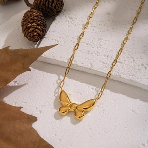 Detail of 18K gold-plated butterfly pendant necklace on a natural white stone base
