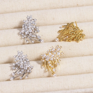Detailed close-up of gold and silver pearl stud earrings with sparkling cubic zirconia clusters