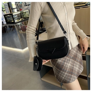 Détail du sac bandoulière en cuir noir avec boucle triangulaire et petit porte-monnaie