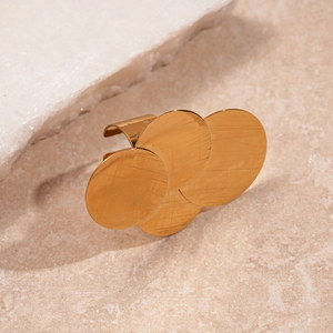 Macro shot of tiered golden brushed metal discs on a minimalist stone surface