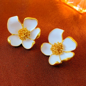 Macro detail of vintage floral earrings with white enamel petals and gold centers