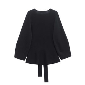 Detail of black long-sleeve knit top featuring a peplum hem and decorative wide waist ties