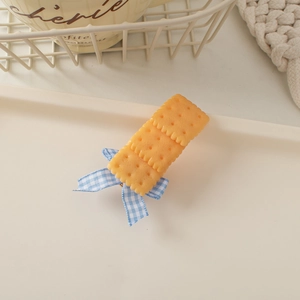 Close-up of cute biscuit hair clip with blue plaid bow on a creamy decorative tray