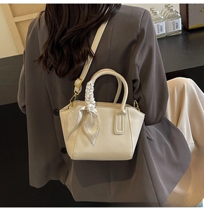 Close-up of beige lychee texture bucket bag with silk scarf and adjustable gold hardware