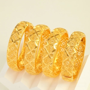 Close-up of four gold vintage bracelets featuring intricate hollow floral carvings and patterns