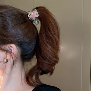 Detail of silver claw clip with pink glitter star securing a high ponytail hair style