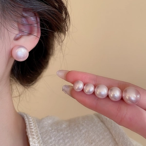 Macro detail of various sizes of round pink pearl earrings with soft mother-of-pearl luster