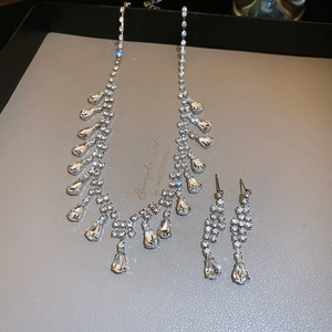 Close-up of teardrop tassel necklace and earring set with shimmering silver crystals