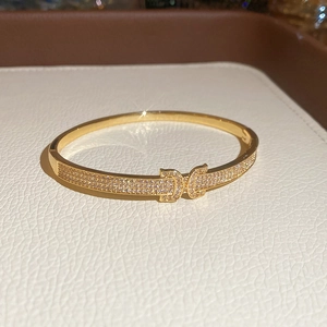Gros plan d'un bracelet doré orné de zircons pavés et d'un fermoir à double C élégant
